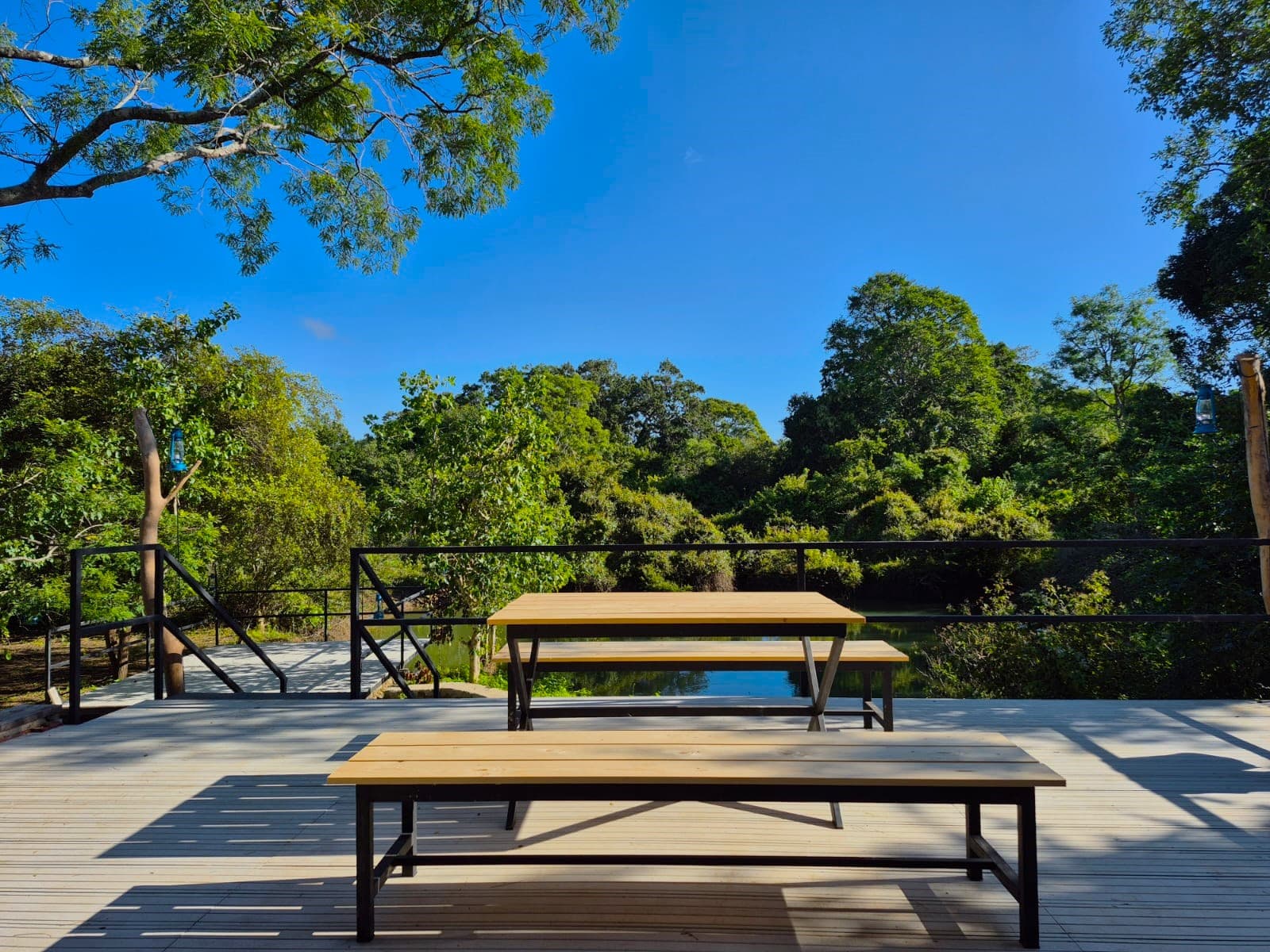 Long timber tables and benches on the open deck under a clear sky