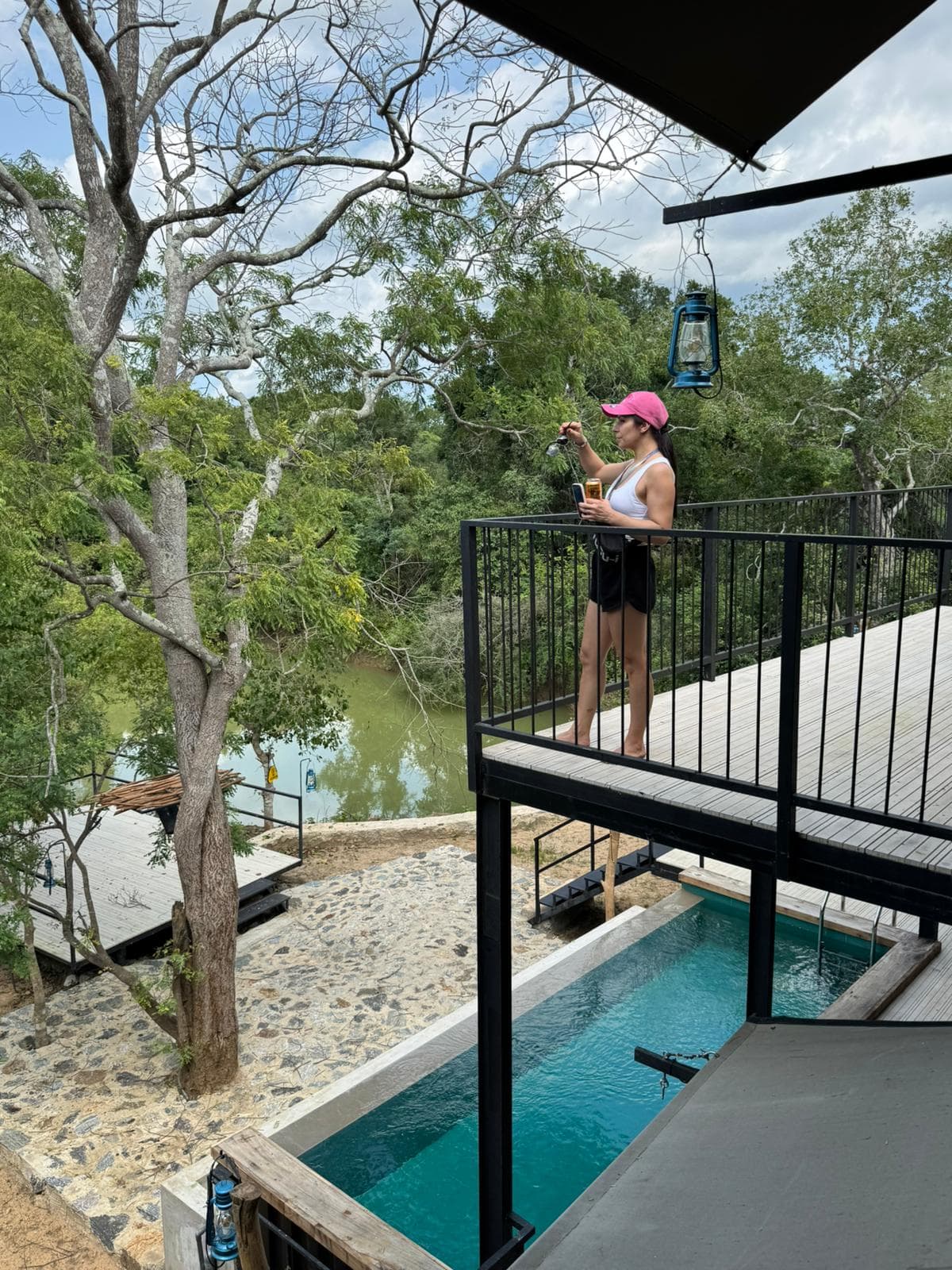 A guest standing at the deck rail above the pool, looking out over the water